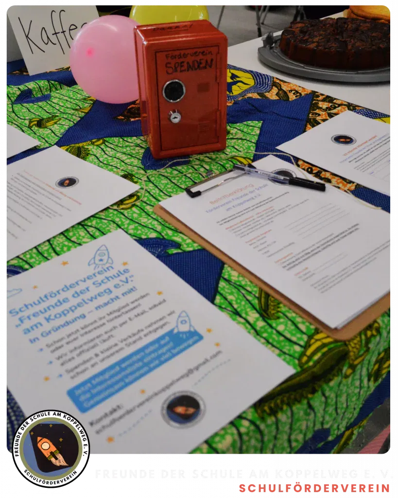 ein bunter tisch mit informationsflyern, klemmbrettern, einer roten spendenbox mit der aufschrift spenden, rosa und gelben luftballons und kuchen im hintergrund. die flyer sind mit einer raketengrafik und deutschem text versehen.